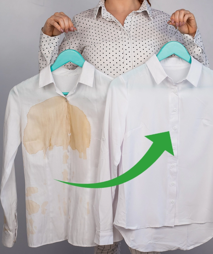 A person holds two white shirts, one stained and one clean, on hangers. A green arrow points from the stained shirt to the clean shirt.